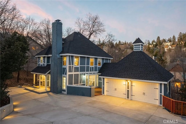 28164 N Bay Rd, Lake Arrowhead, CA 92352 - back of property at dusk with a chimney, a shingled roof, a garage, and concrete driveway