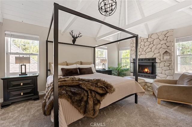 carpeted bedroom featuring beam ceiling, multiple windows, a fireplace, and wood ceiling