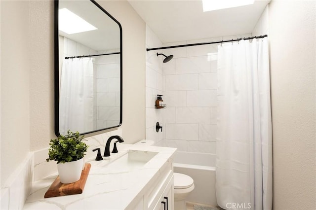 full bathroom featuring shower / bathtub combination with curtain, vanity, a skylight, and toilet