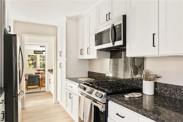 kitchen featuring tasteful backsplash, stainless steel appliances, dark stone countertops, white cabinets, and light hardwood / wood-style floors