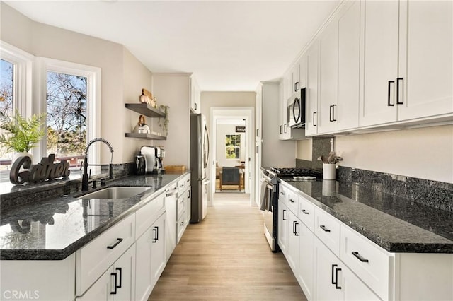 28164 N Bay Rd, Lake Arrowhead, CA 92352 - kitchen with appliances with stainless steel finishes, open shelves, light wood-style floors, white cabinetry, and dark stone counters