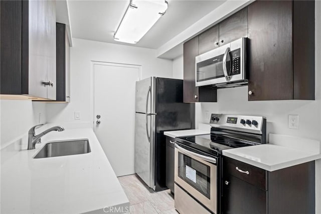 kitchen featuring dark brown cabinets, light hardwood / wood-style floors, sink, and stainless steel appliances