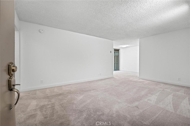 unfurnished room with light colored carpet and a textured ceiling