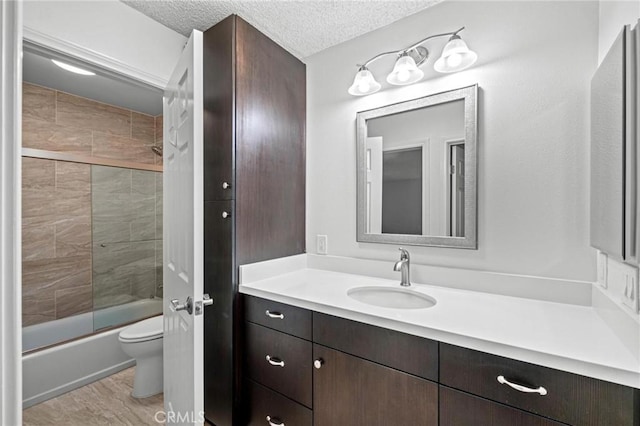 full bathroom featuring toilet, combined bath / shower with glass door, a textured ceiling, and vanity