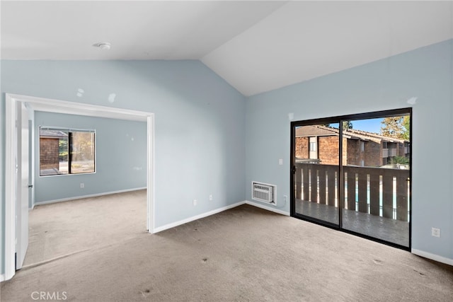 empty room with carpet flooring, a wall mounted AC, and vaulted ceiling