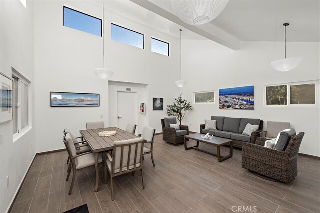 dining area featuring beamed ceiling, high vaulted ceiling, and wood-type flooring