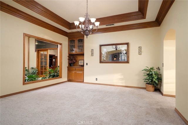 carpeted empty room with a tray ceiling, crown molding, and a notable chandelier