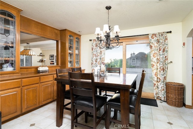 tiled dining area featuring a chandelier and a textured ceiling