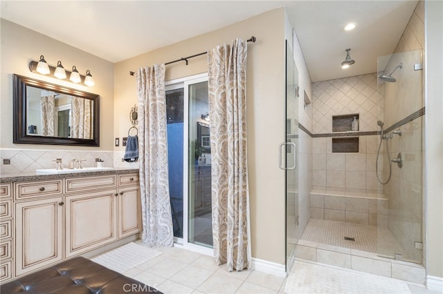 bathroom featuring tile patterned floors, backsplash, vanity, and a shower with shower door