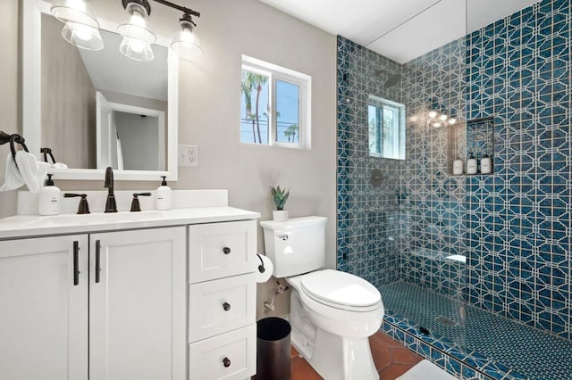 bathroom with tiled shower, vanity, and toilet