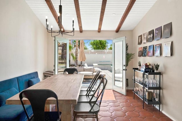 dining space featuring lofted ceiling with beams, dark tile patterned flooring, a healthy amount of sunlight, and a notable chandelier