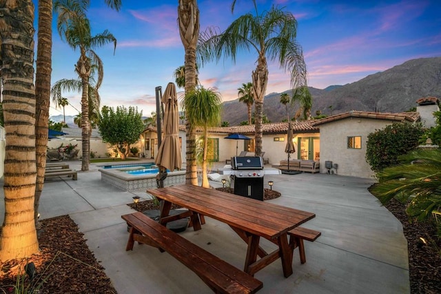 patio terrace at dusk featuring a mountain view and an in ground hot tub