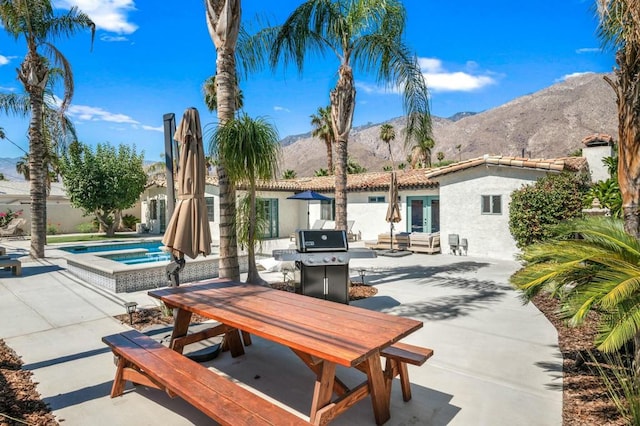 view of patio featuring a swimming pool with hot tub, grilling area, a mountain view, and french doors