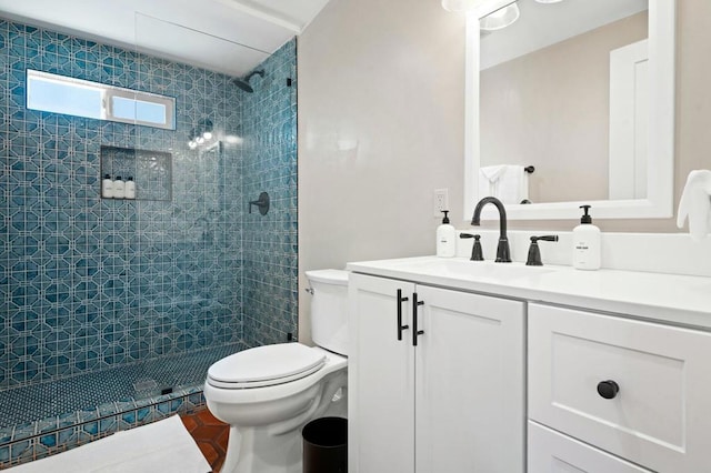 bathroom with vanity, toilet, and a tile shower