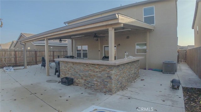 view of patio featuring ceiling fan and a bar