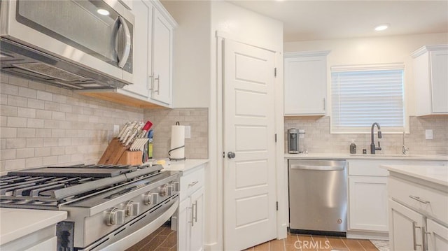 kitchen with stainless steel appliances, white cabinetry, sink, and decorative backsplash