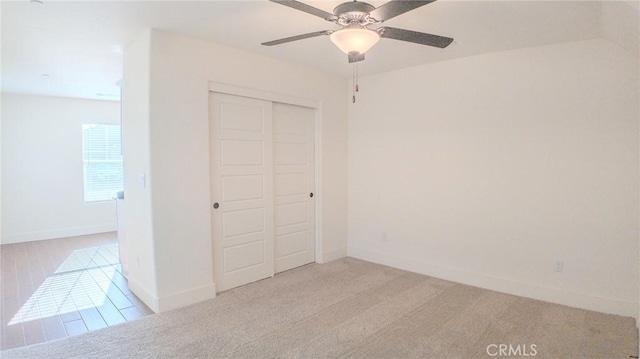 unfurnished bedroom featuring light carpet, a closet, and ceiling fan