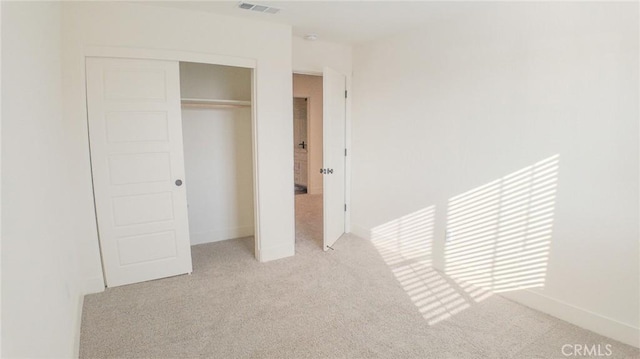 unfurnished bedroom with light colored carpet and a closet