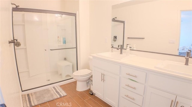 bathroom featuring vanity, a shower with shower door, and toilet