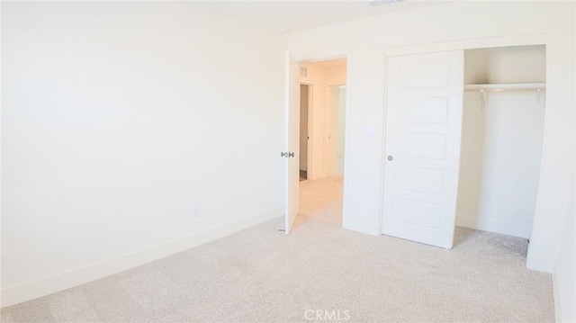 unfurnished bedroom featuring light colored carpet and a closet