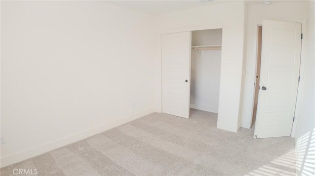 unfurnished bedroom featuring light carpet and a closet