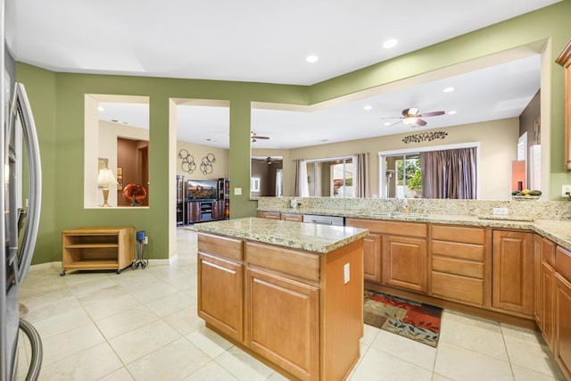 kitchen with light stone countertops, a center island, sink, and appliances with stainless steel finishes