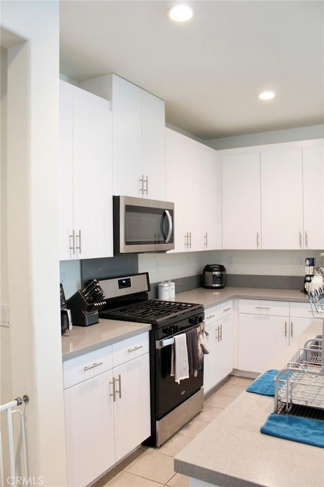 kitchen featuring white cabinets, light tile patterned flooring, and appliances with stainless steel finishes