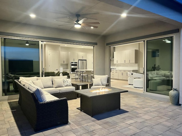 view of patio with ceiling fan and an outdoor living space with a fire pit