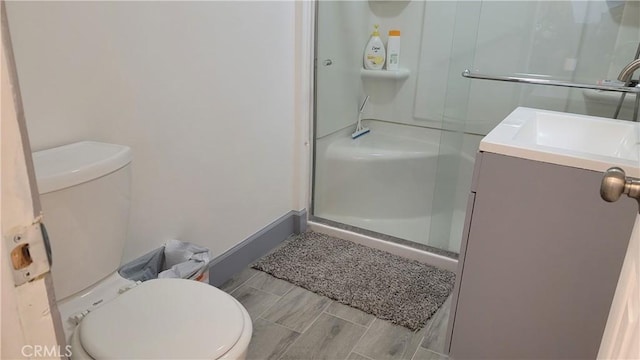 bathroom featuring hardwood / wood-style flooring, a shower with door, vanity, and toilet