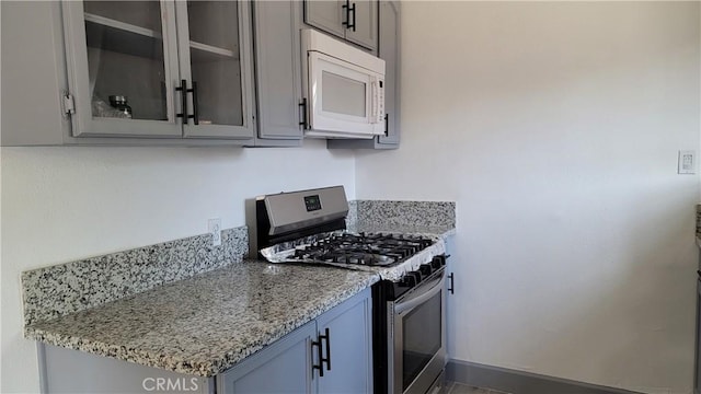 kitchen featuring gas stove and light stone counters