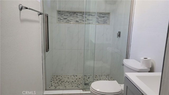 bathroom featuring tile patterned flooring, vanity, toilet, and a shower with shower door