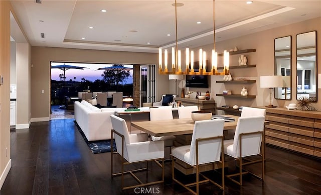 dining area with a tray ceiling and dark wood-type flooring