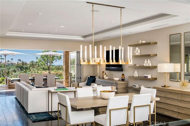 dining area with dark wood-type flooring and a tray ceiling