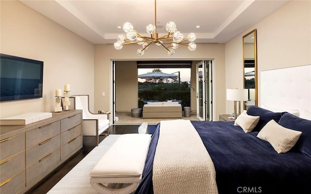 bedroom with a raised ceiling, dark hardwood / wood-style floors, and a notable chandelier