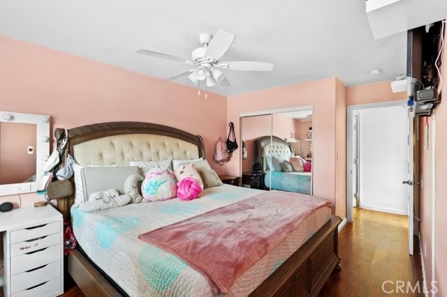 bedroom with a closet, dark wood-type flooring, and ceiling fan