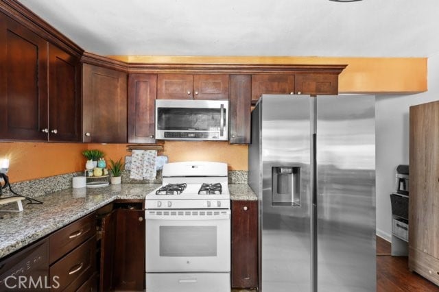 kitchen featuring light stone counters, dark hardwood / wood-style flooring, and appliances with stainless steel finishes