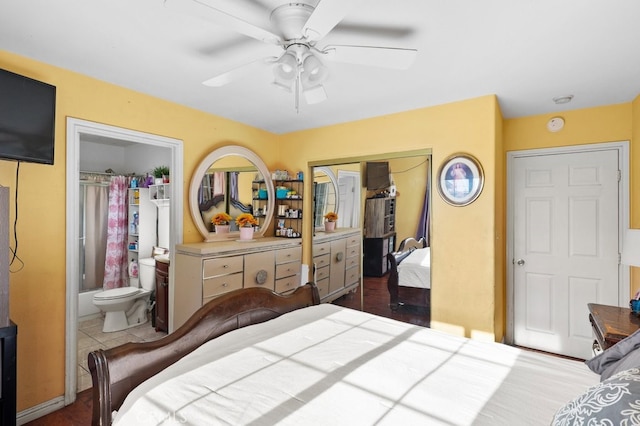 bedroom featuring ceiling fan, dark tile patterned floors, ensuite bathroom, and a closet