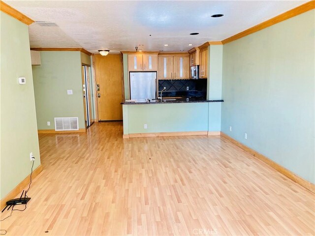 kitchen with kitchen peninsula, light wood-type flooring, decorative backsplash, appliances with stainless steel finishes, and ornamental molding