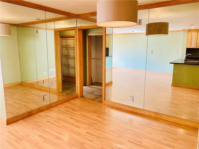 spare room featuring beamed ceiling, light wood-type flooring, and sink