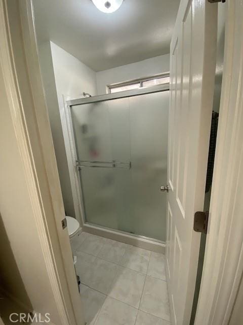 bathroom featuring toilet, tile patterned flooring, and a shower with door