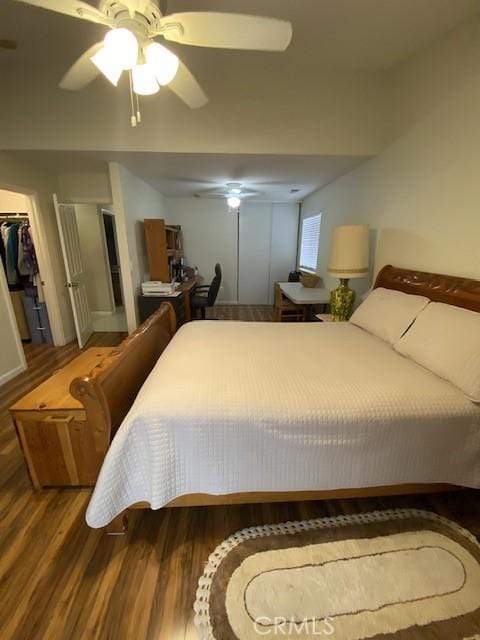 bedroom featuring a spacious closet, wood-type flooring, a closet, and ceiling fan