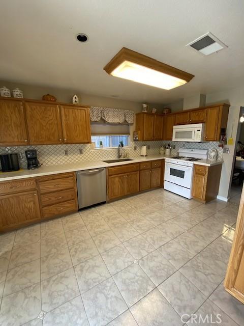 kitchen with sink, white appliances, and backsplash