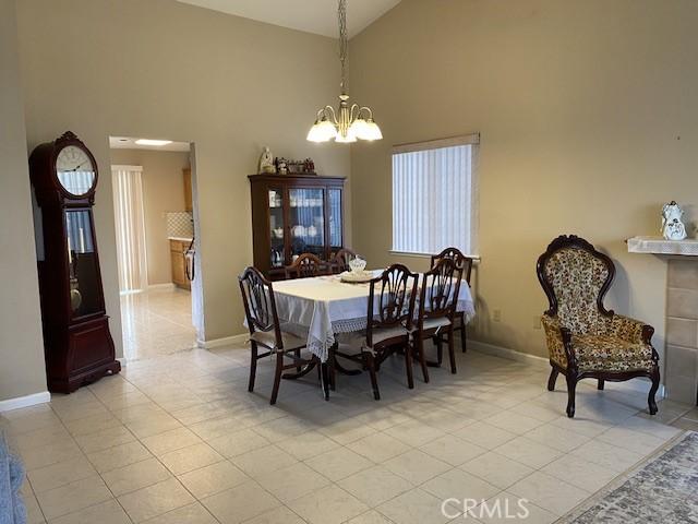 tiled dining space featuring high vaulted ceiling and a notable chandelier