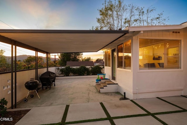 patio terrace at dusk featuring a grill