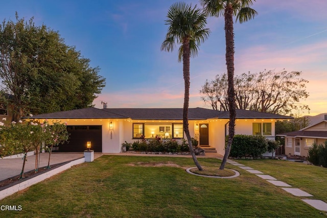 ranch-style house with a garage and a yard