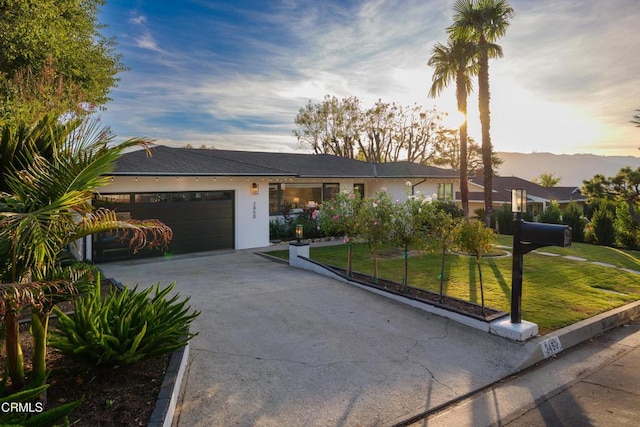 ranch-style home featuring a lawn and a garage