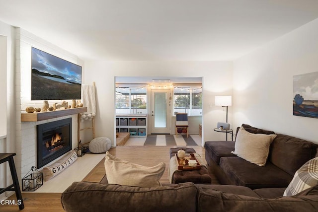 living room with light wood-type flooring and a brick fireplace