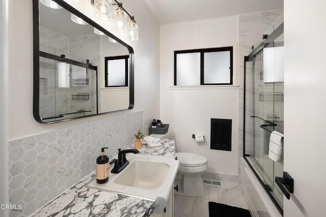 full bathroom featuring toilet, combined bath / shower with glass door, and vanity