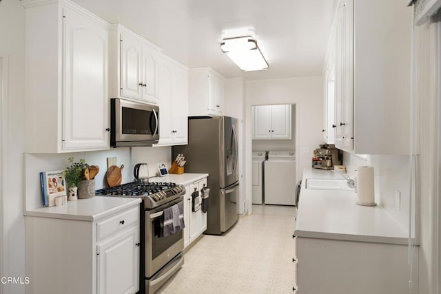 kitchen with appliances with stainless steel finishes, separate washer and dryer, white cabinetry, and sink