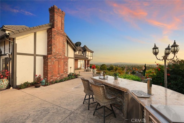 patio terrace at dusk featuring an outdoor bar